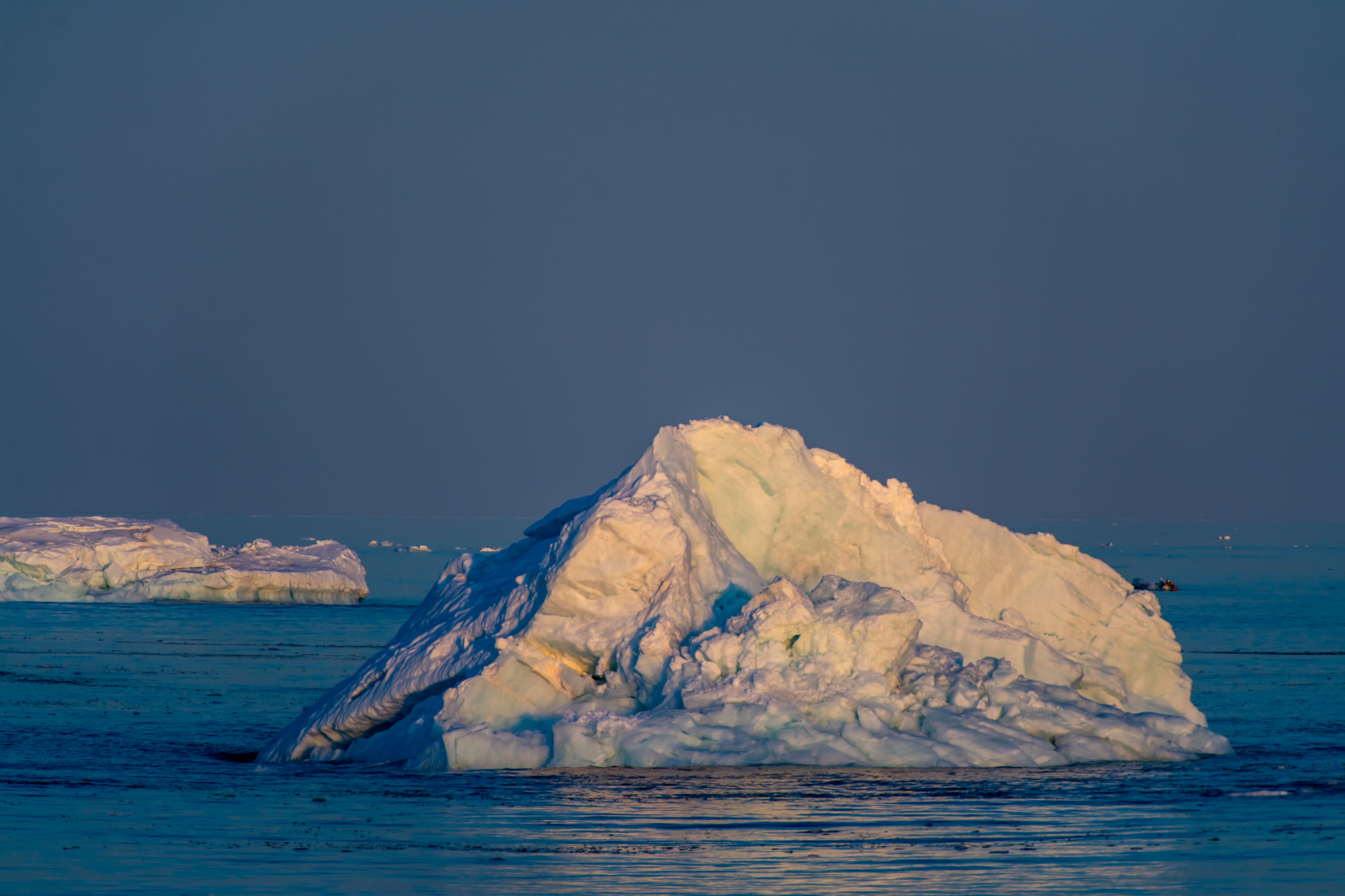 Eisberg vor dunkelblauem Wasser auf Spitzbergen, Seevögel sitzen auf dem Eis