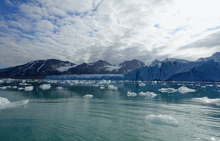 Gletscherfront in Nordspitzbergen mit Treibeis im Vordergrund und Bergen im Hintergrund